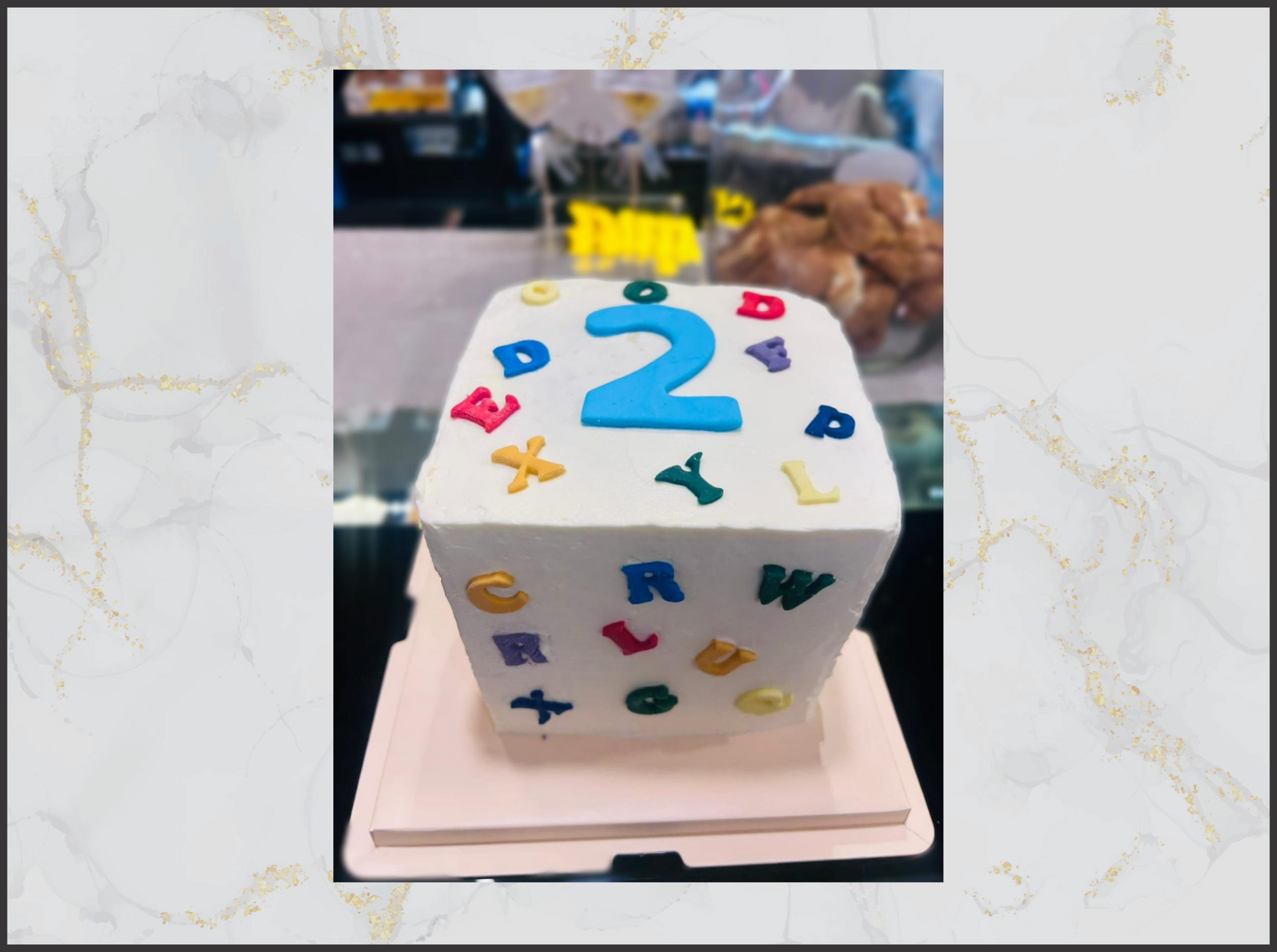 Cube-shaped cake with colorful letters and number '2' macau cake